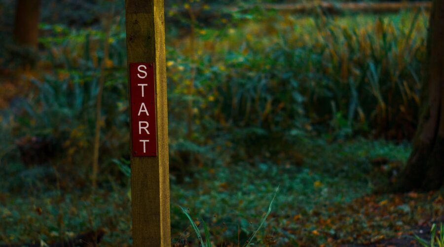 A wooden pole in the woods that says "start" as a representation for my triathlons for newbies post trying to answer the question: what is a triathlon?